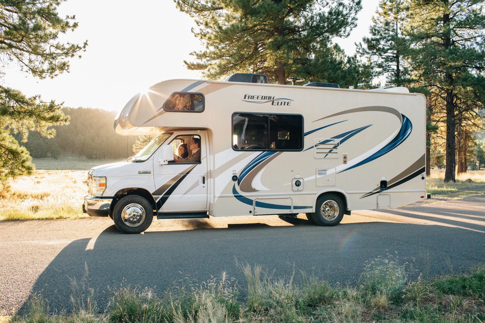 Class C motorhome pulling out onto a road with trees in the background